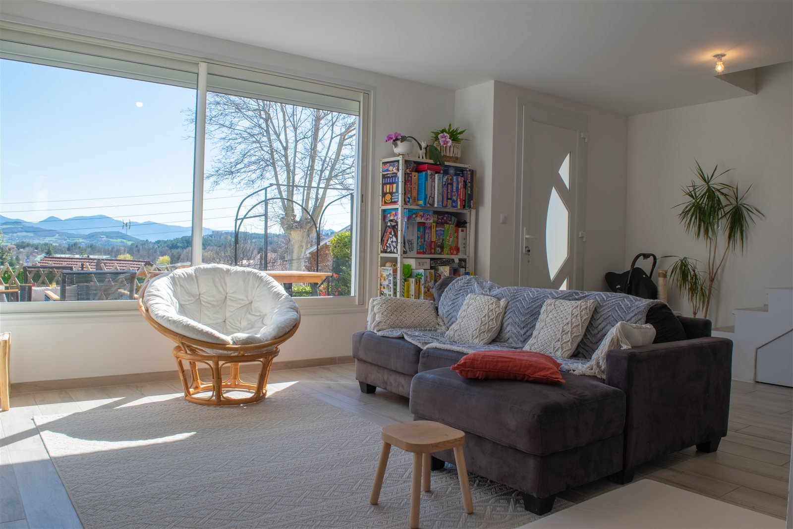Salon avec canapé, fauteuil et grande baie vitrée donnant sur les montagnes